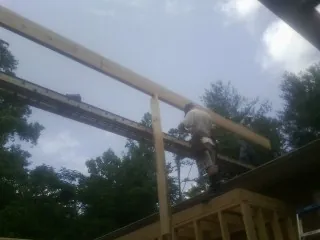 Carpenter setting a ridge beam over a new addition frame — Ice Dam Removal by Roofing Brothers in Rippey