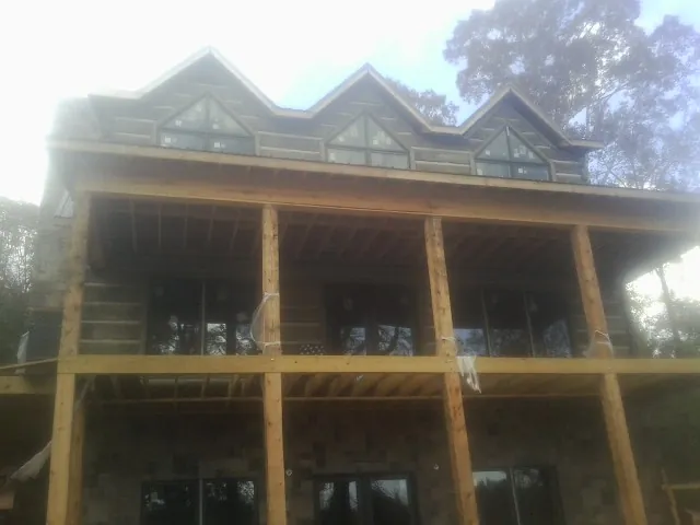 Dormers and porch framing on a large log home under construction — Roof Coating work by our crew in Rippey