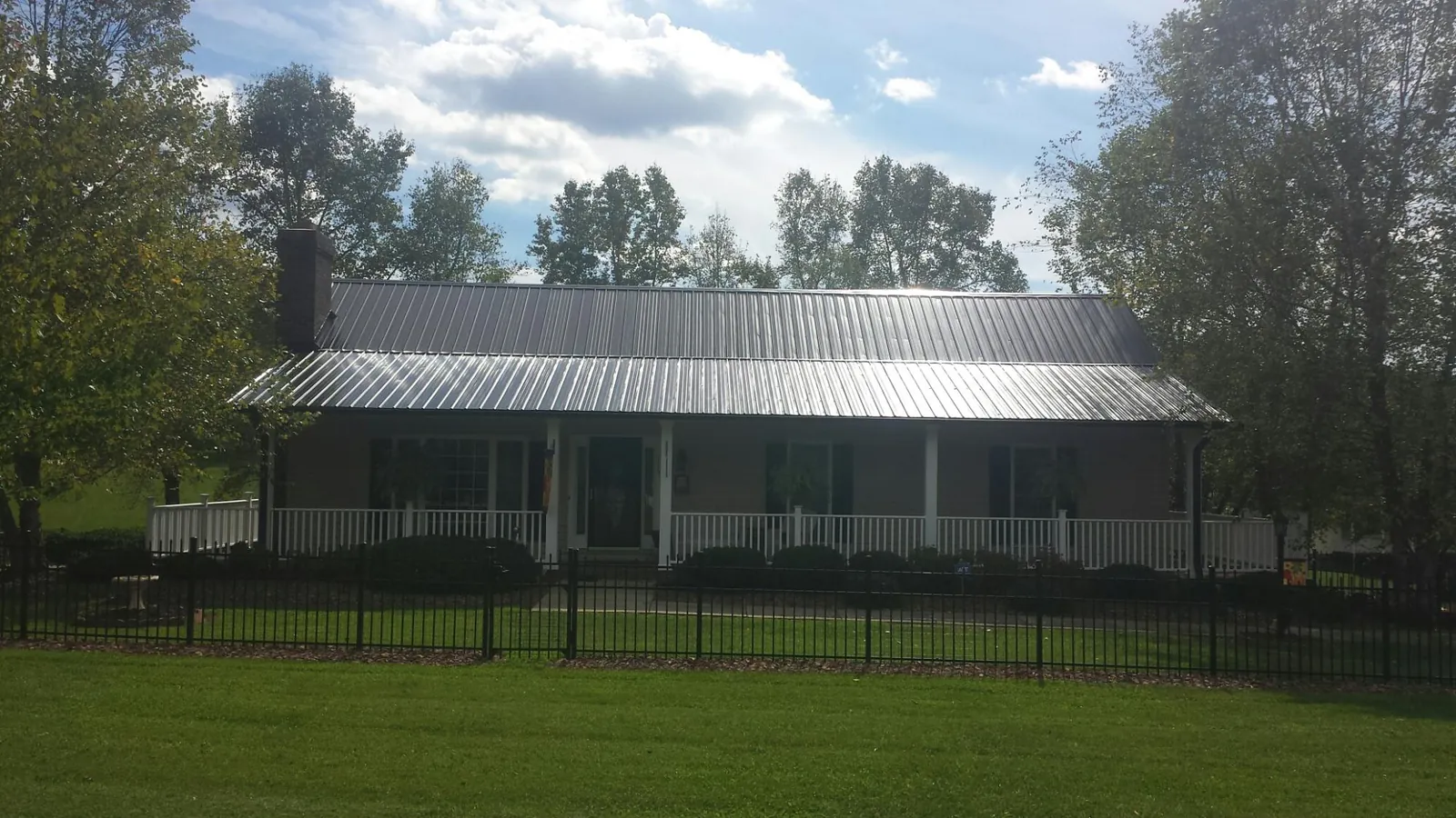 Gray metal roof on a brick ranch with a full width front porch — Gutter Guard Installation work by our crew in Rippey