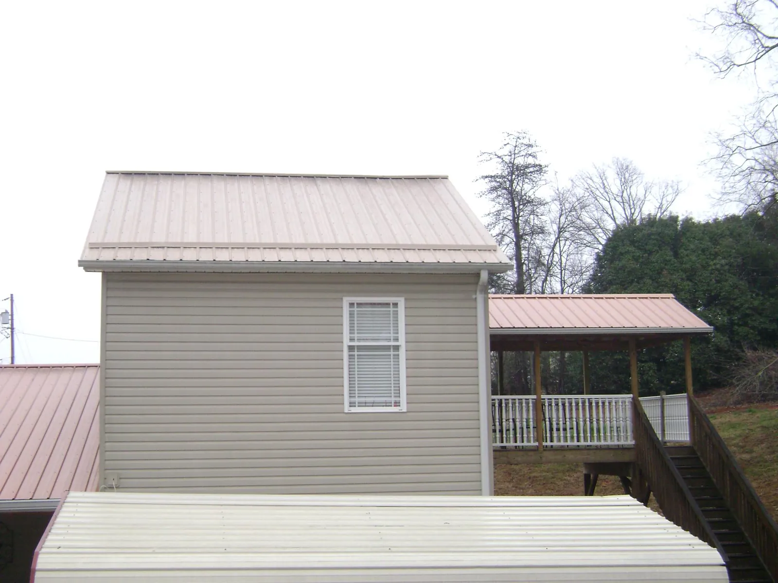 Tan metal roofs on a two story addition and attached porch, from a Roof Replacement job in Rippey