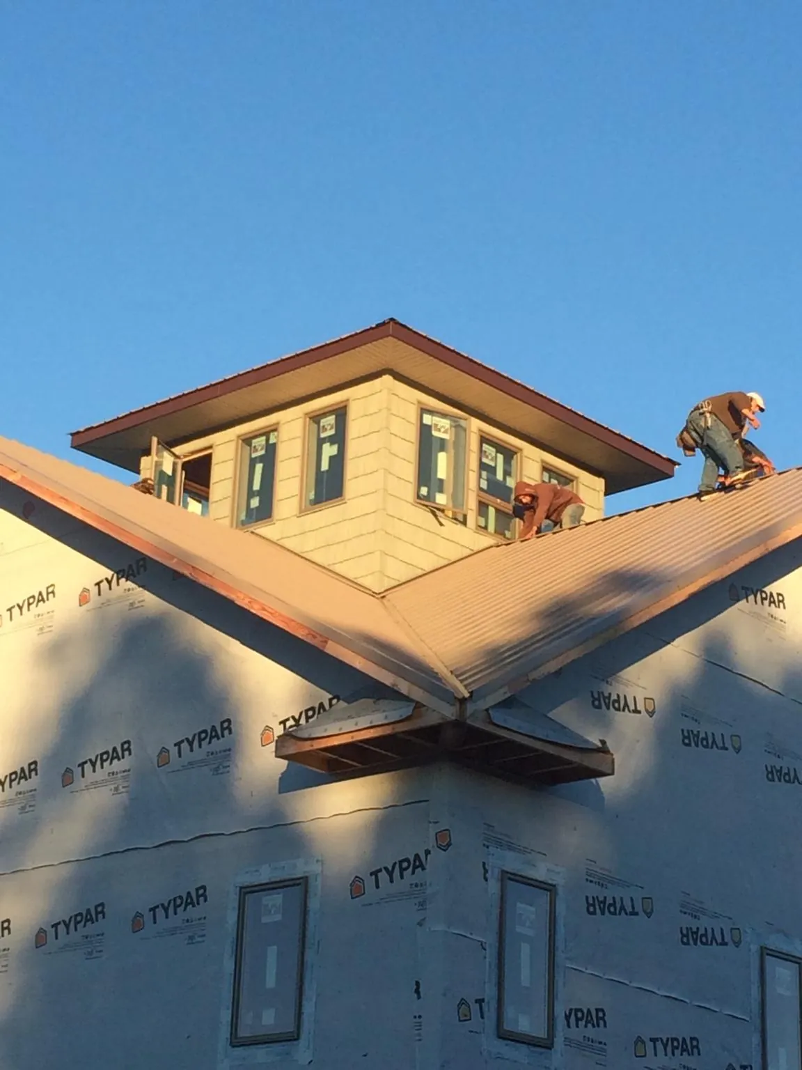 Roofers working around a rooftop cupola on a new metal roof at sunset — Roof Waterproofing in Rippey by Roofing Brothers